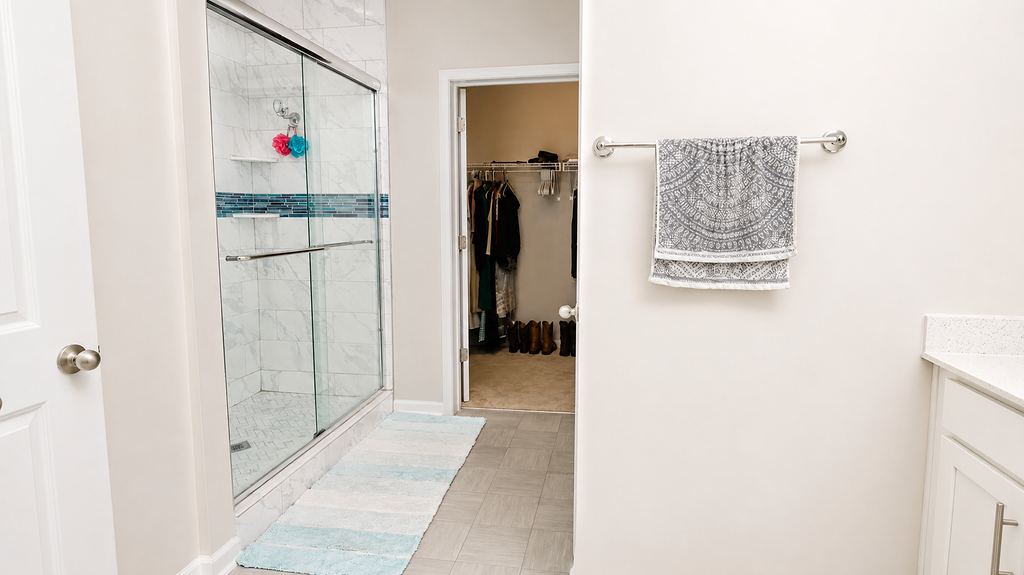 Primary bathroom with updated tile-and-glass shower and walk-in closet access