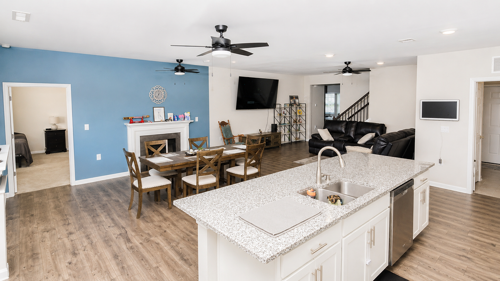 Open-concept great room with granite island, fireplace and blue accent wall